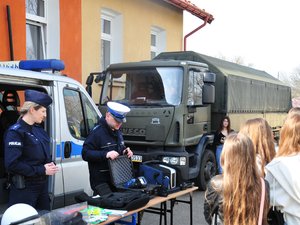 Na zdjęciu widoczna jest policjantka oraz policjant pokazujący wyposażenie policjantów ruchu drogowego