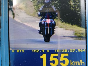 Ekran ręcznego miernika prędkości, na którym widać motocykl, godzinę pomiaru oraz prędkość