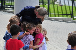 Kilkoro dzieci uśmiechniętych i przytulających się do policjantki