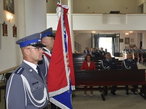 Poczet sztandarowy, w tle zgromadzeni goście siedzący w kościelnych ławkach