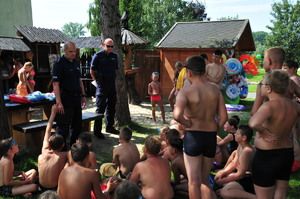 Dwójka policjantów mówiących do dzieci siedzących na trawie