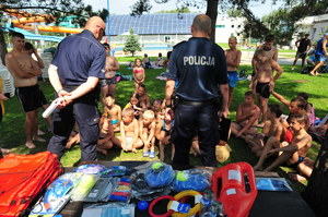 Dwójka policjantów mówiących do dzieci siedzących na trawie