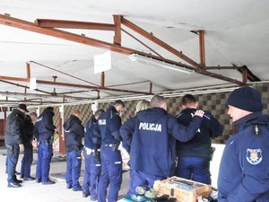 Policjanci stoją w szeregu podczas sprawdzenia broni przez instruktorów