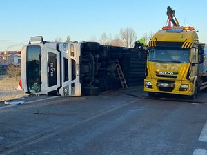 Wywrócony pojazd, obok którego stoi samochód pomocy drogowej