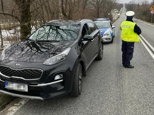 Pojazd sprawców, za nim radiowóz, obok policjant ruchu drogowego