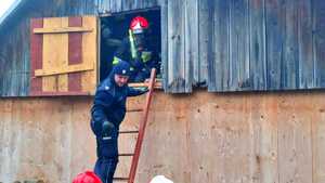 Policjant stojący na drabinie, na poddaszu strażak