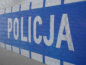 Napis Policja na niebieskim tle znajdujący się na drzwiach radiowozu