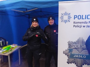 Policjantka robiąca z dłoni serce. Obok stoi drugi policjant.