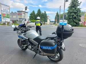 Policjant ruchu drogowego stojący przy motocyklu na skrzyżowaniu