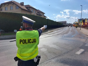 Policjant ruchu drogowego stojący na skrzyżowaniu i wskazujący kierunek jazdy