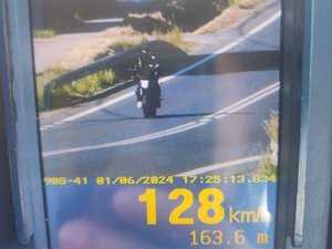 Ekran ręcznego miernika prędkości z zarejestrowaną prędkością 128 km/h oraz motocyklem