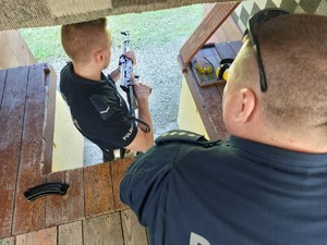 Policjant trzymający karabinek. Obok niego instruktor