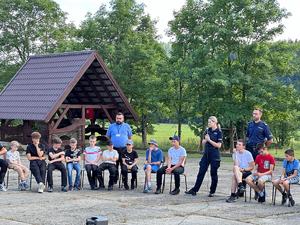 Uczestnicy siedzący w koło i słuchający stojących policjantów