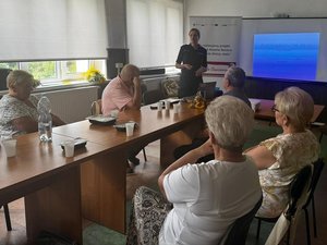 Policjantka mówiąca do siedzących przy stołach seniorów