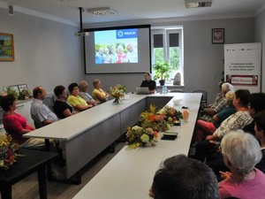 Policjantka mówiąca do siedzących przy stołach seniorów