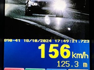 Ekran ręcznego miernika prędkości z wynikiem 156 km/h i wizerunkiem samochodu