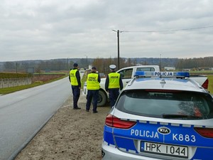 Na zdjęciu widoczny policjant, radiowóz oraz dwóch funkcjonariuszy SOK. W tle przejazd kolejowy