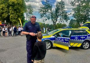 Policjant rozmawiający z dzieckiem obok radiowozu