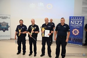 na zdjęciu wiać policjantów stojących w szeregu trzymających w ręku puchary i dyplomy