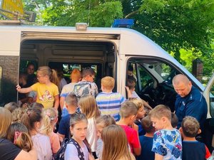 na zdjęciu widoczny policjant, który prezentuje dzieciom radiowóz policyjny