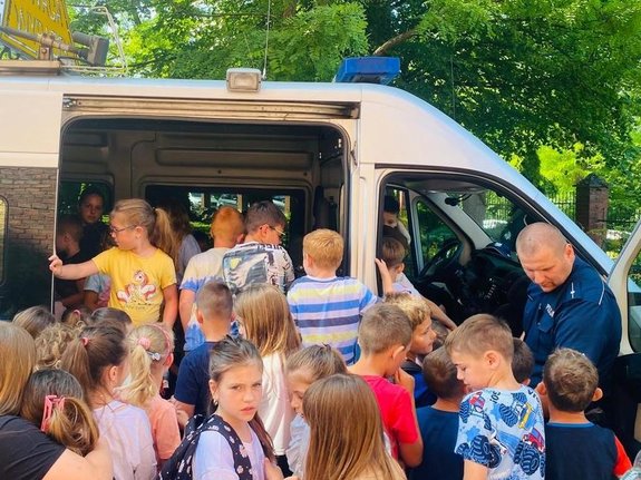 na zdjęciu widoczny policjant, który prezentuje dzieciom radiowóz policyjny