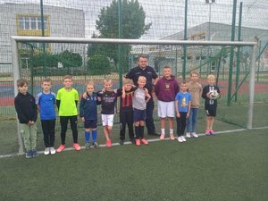 policjant stojący z dziećmi na boisku sportowym