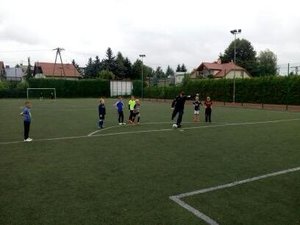 policjant z dziećmi na boisku szkolnym grający w piłkę