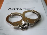 Teczka, na której widnieje napis Akta, a na niej leżą kajdanki