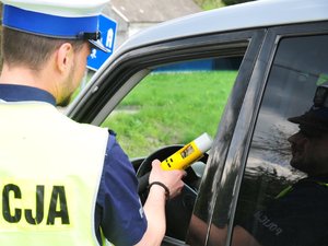 Policjant stojący przy samochodzie i wykonujący badanie trzeźwości