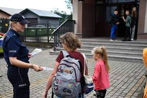 Policjanci z wraz z przedstawicielami komisji rozdający ulotki przed szkołami