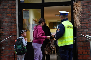 Policjanci z wraz z przedstawicielami komisji rozdający ulotki przed szkołami