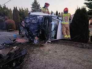 zdjęcie przedstawia samochód biorący udział w zdarzeniu drogowym oraz strażaków