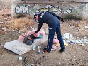 Dzielnicowy pochylający się nad leżącym mężczyzną