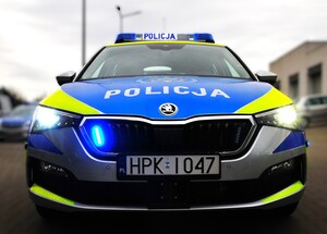 Na zdjęciu widoczny przód radiowozu z włączonymi niebieskimi sygnałami świetlnymi