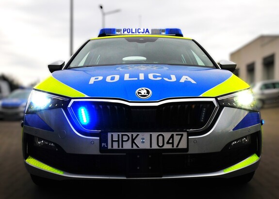 Na zdjęciu widoczny przód radiowozu z włączonymi niebieskimi sygnałami świetlnymi