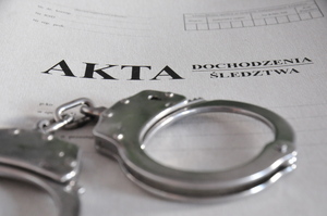 Teczka akt dochodzenia, na której leżą kajdanki