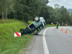 Pojazd leżący na dachu, obok strażak kierujący ruchem.