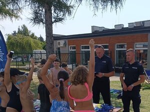 Policjanci rozmawiający z dziećmi na basenie